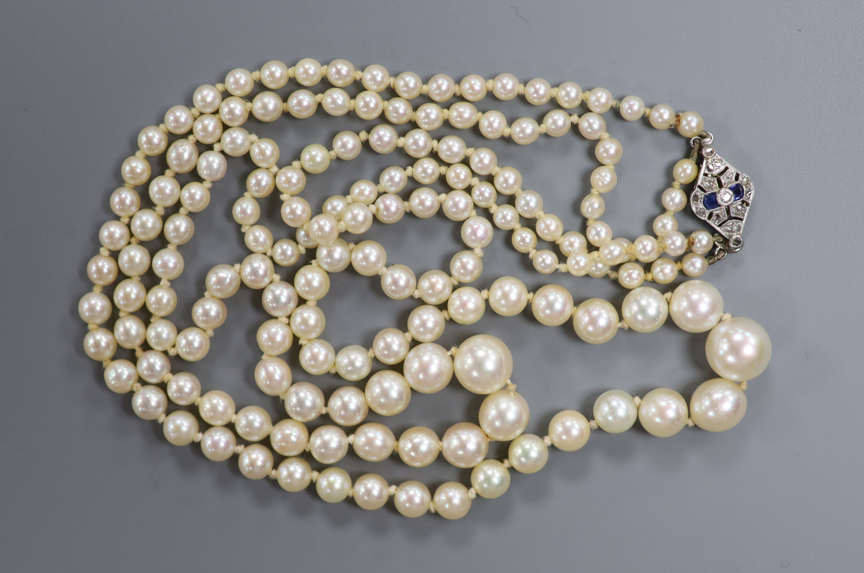 A double strand graduated cultured pearl necklace, with white metal (18ct poincon mark), sapphire and diamond set clasp signed Lacloche Freres and numbered 3763, 46cm, gross weight 33.8 grams